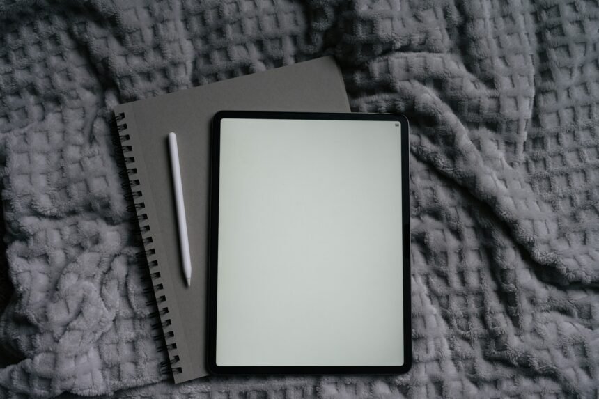 tablet and pen on top of a gray blanket